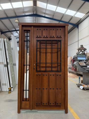 Puerta rústica de madera con clavos y reja grande, fabricada a medida en Guadalajara